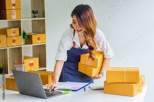 Small business owner looking at company's past online sales, cropped image of woman holding her own box for delivery at online sales office, merchandising concept and modern businessman.