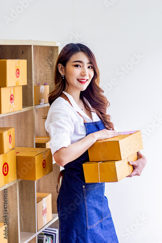 Small business owner looking at company's past online sales, cropped image of woman holding her own box for delivery at online sales office, merchandising concept and modern businessman.
