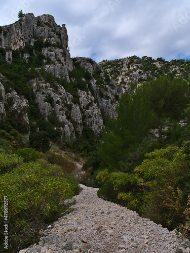 Rocky hiking trail on slope in Calanques National Park near Cassis, French Riviera at the mediterranean cost with rugged rocks and green vegetation.