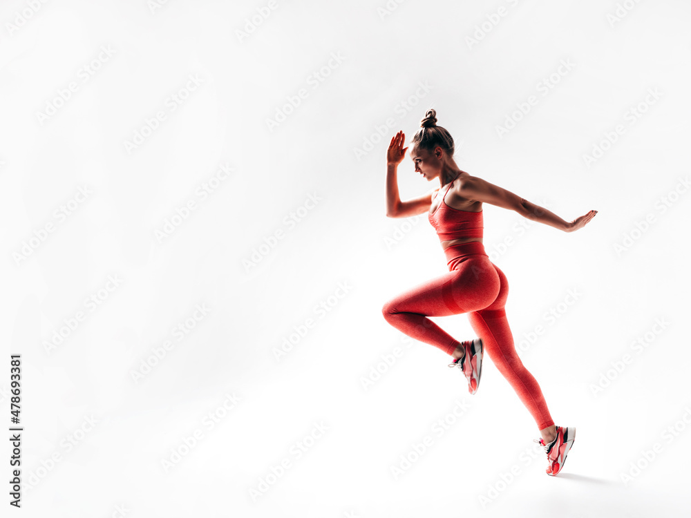 Fitness confident woman in pink sports clothing. Sexy young beautiful model with perfect body. Female isolated  on white in studio. Cheerful and happy. Jumping and running