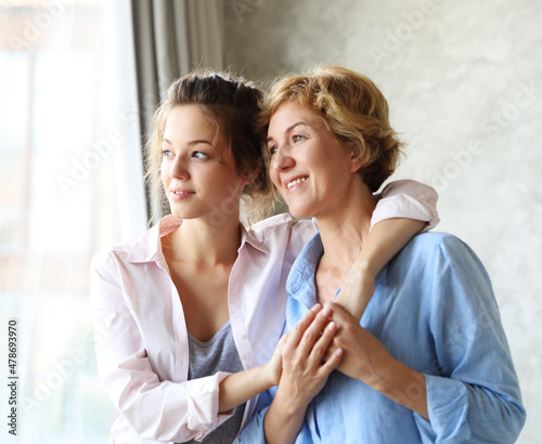 Happy senior mother embracing adult daughter laughing together