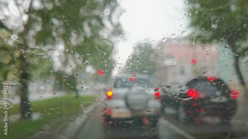 City rain. Inside car view. Autumn danger. Automobile wet travel. Bad cold weather. Vehicle window. Town traffic. People on street. Staycation concept. Focus on spray drop