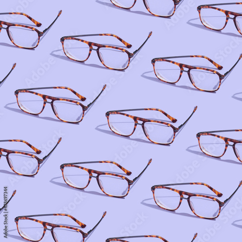 Pattern made with retro glasses on purple background. Creative vision composition.