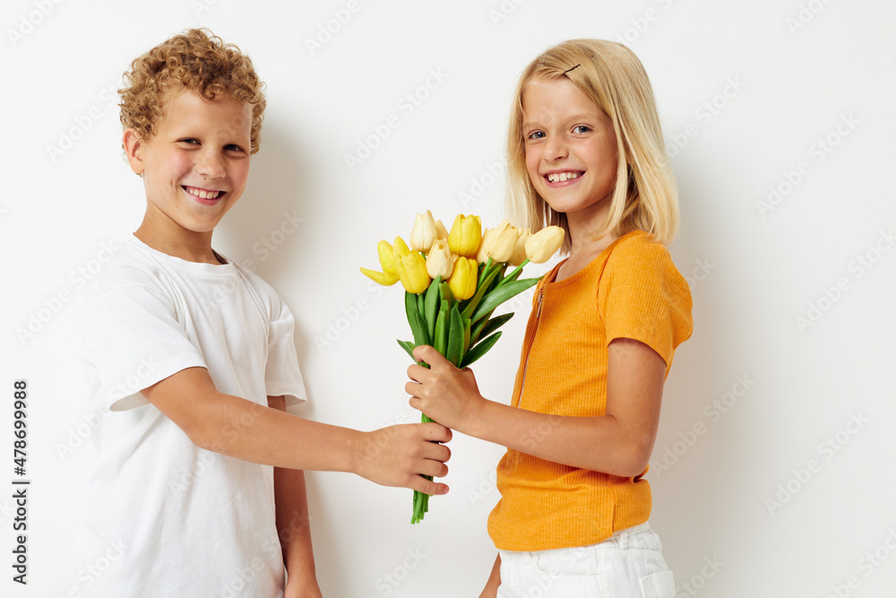 Cute preschool kids with a bouquet of flowers gift birthday holiday childhood light background Cute preschool kids with a bouquet of flowers gift birthday holiday childhood light background