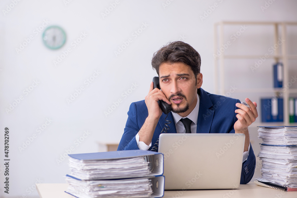 Young male employee and too much work in the office Young male employee and too much work in the office