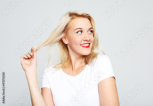 Beautiful happy girl touches her hair. Casual clothes.
