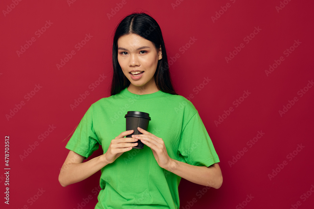 woman with Asian appearance in a green t-shirt a glass of drink fun isolated background unaltered woman with Asian appearance in a green t-shirt a glass of drink fun isolated background unaltered