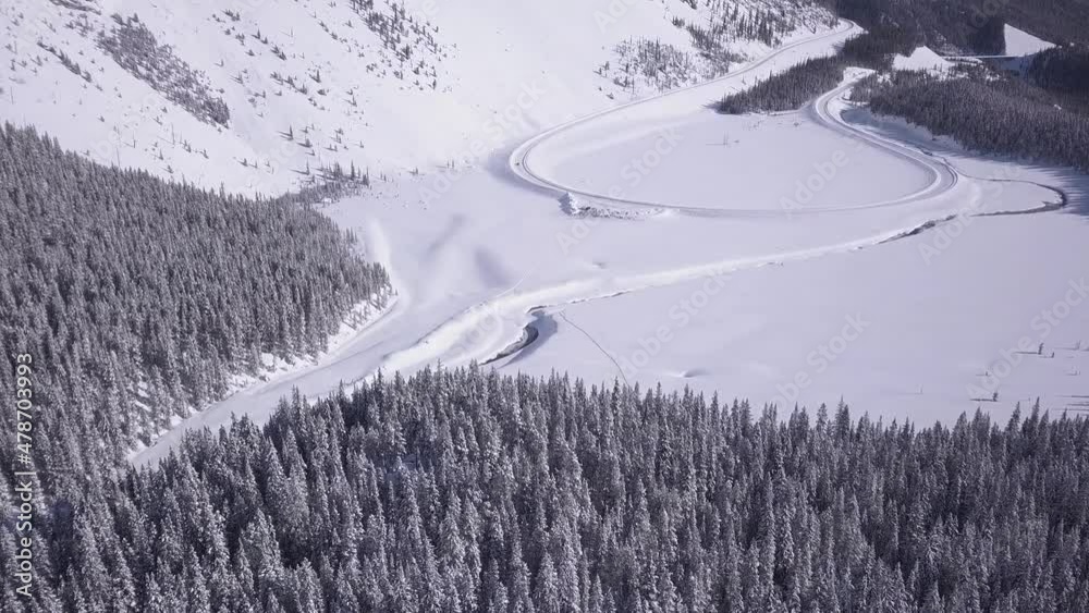 Cold winter aerial descent to snowy highway loop at base of big hill Cold winter aerial descent to snowy highway loop at base of big hill