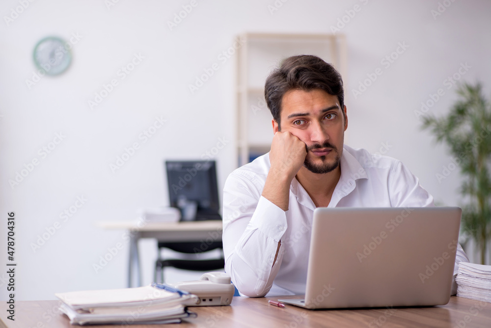 Young male employee and too much work in the office Young male employee and too much work in the office