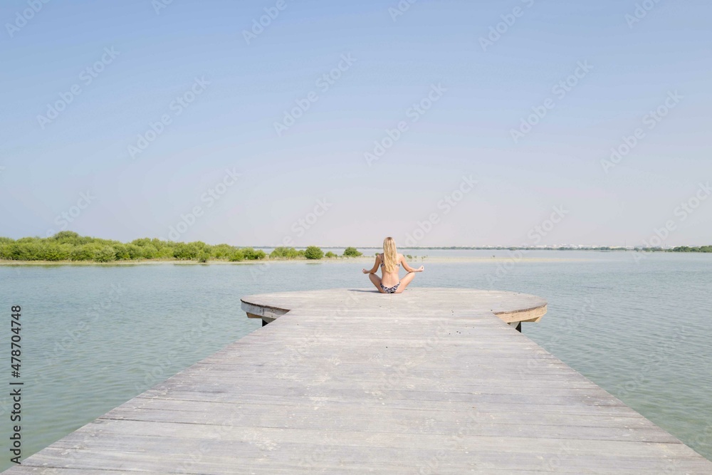 Woman meditating on the wooden platform Woman meditating on the wooden platform