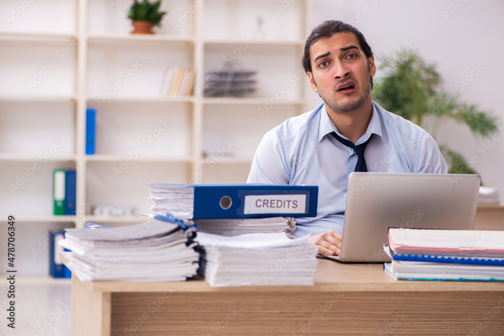 Young male employee and too much work in the office Young male employee and too much work in the office