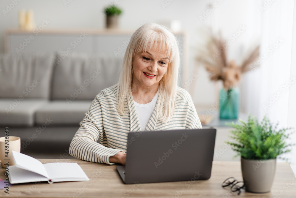 Mature woman sitting at desk and working on pc Mature woman sitting at desk and working on pc