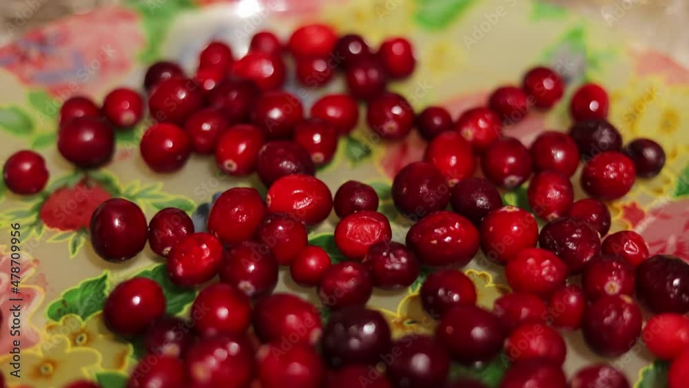 Close up of a bunch of red cranberries spread across a flowery plate Close up of a bunch of red cranberries spread across a flowery plate