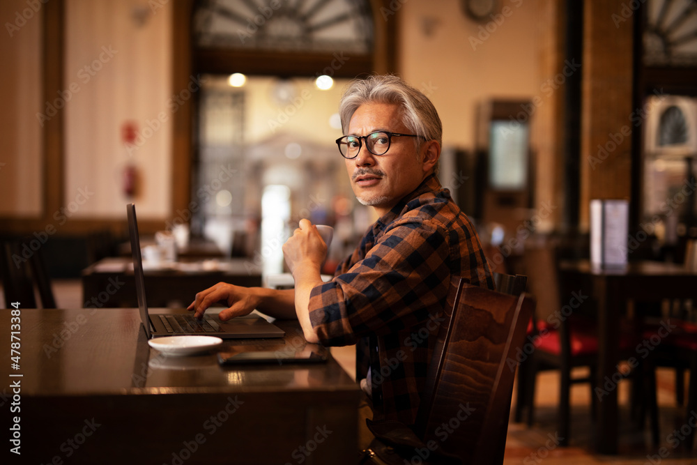 Businessman working on laptop in cafe. Handsome senior man enjoying in fresh coffee