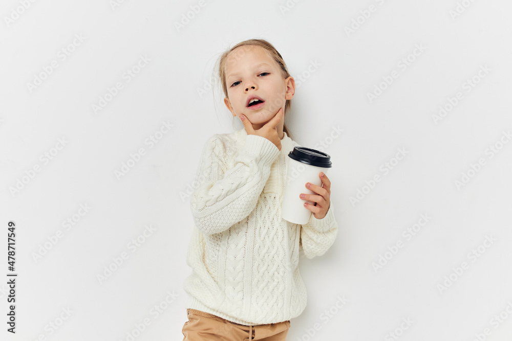 little girl in white sweater glass with drink light background little girl in white sweater glass with drink light background