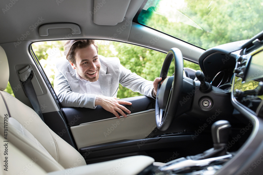 Satisfied customer. Guy looking at auto interior, choose new automobile in dealership store Satisfied customer. Guy looking at auto interior, choose new automobile in dealership store