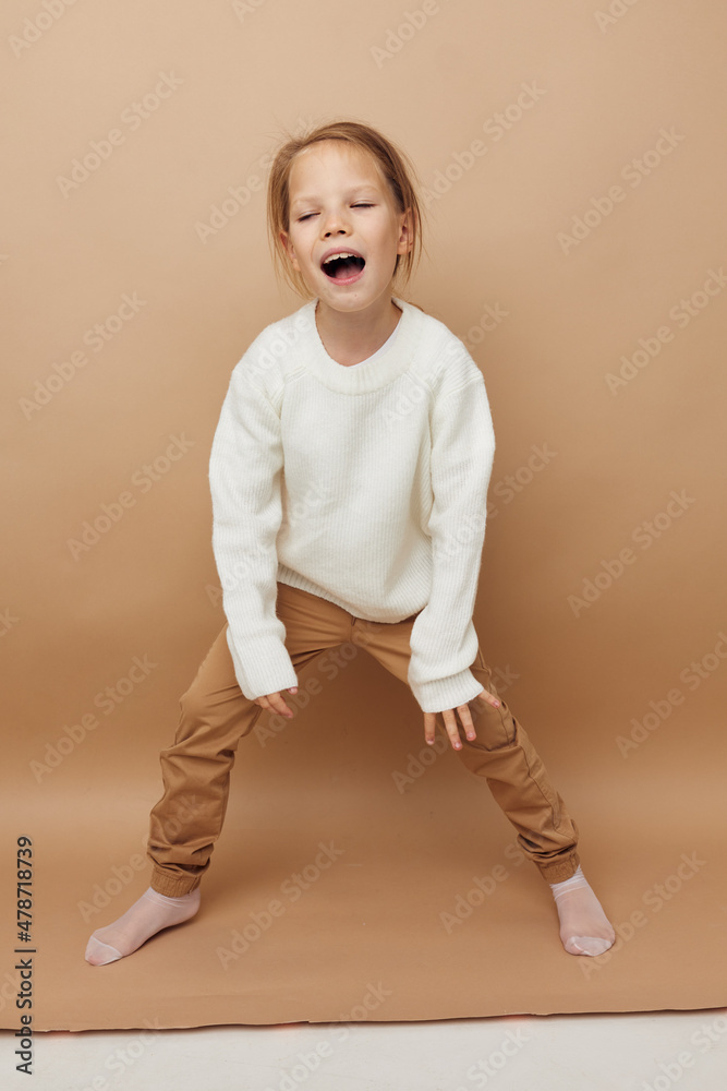 Portrait of happy smiling child girl in white sweater posing hand gestures Lifestyle unaltered