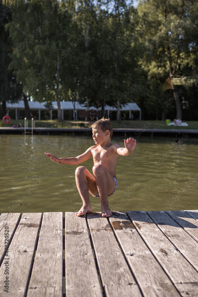 boy jumping from a trampoline into the pool. Children jump on inflatable water slide. Aqua amusement park in exotic island resort. boy jumping from a trampoline into the pool. Children jump on inflatable water slide. Aqua amusement park in exotic island resort.