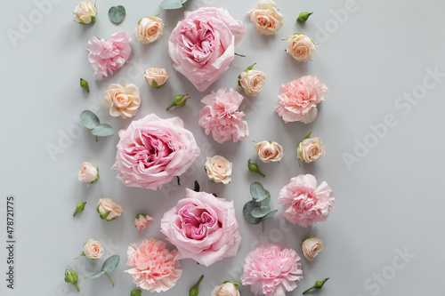 Beautiful flowers on a light gray background, roses, carnations, buds and greenery. Floral background, greeting card. Top view, copy space.