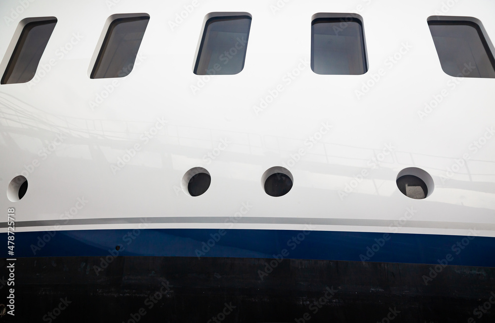 Portholes on the hull of a luxury yacht, above the waterline, side view.