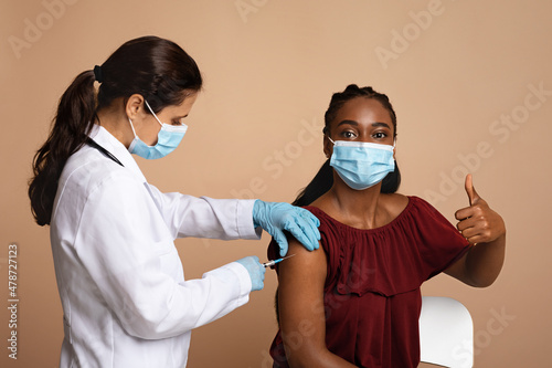 Young black woman in face mask getting vaccinated