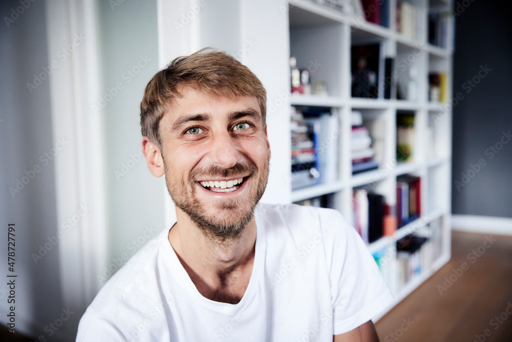 Smiling man in front of bookshelf at home Smiling man in front of bookshelf at home