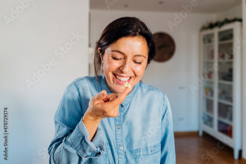 Cheerful woman tasting food with finger at home photo