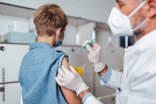 Healthcare worker administering boy with COVID-19 vaccine at vaccination center photo