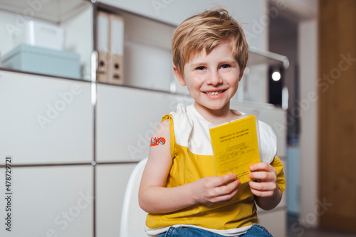 Happy boy holding immunization certificate at center photo