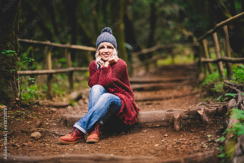 Smiling woman with hands on chin sitting in forest Smiling woman with hands on chin sitting in forest