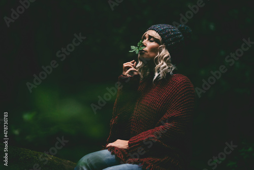 Woman smelling green leaf in forest photo