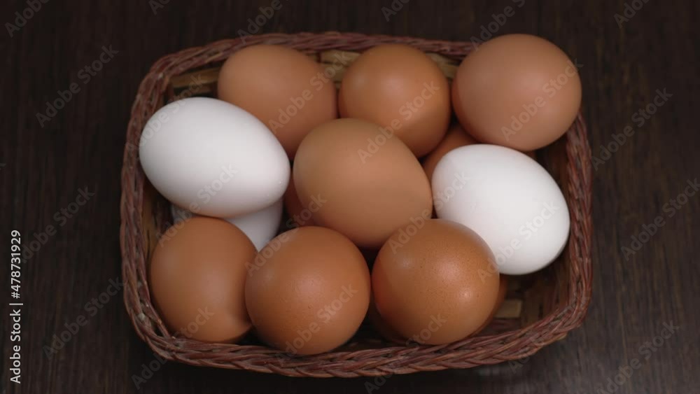 The camera smoothly approaches from the front and from above to the chicken eggs lying in the basket. Brown and white eggs on the table. Close-up shooting. A useful product without harmful impurities. The camera smoothly approaches from the front and from above to the chicken eggs lying in the basket. Brown and white eggs on the table. Close-up shooting. A useful product without harmful impurities.