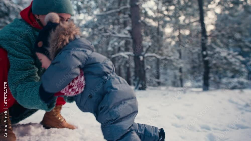 Mother learning her little baby his first steps in the snow forest. High quality 4k footage