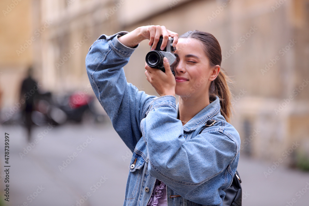 Young Woman In City Street Taking Photo On Retro Style Digital Camera To Post To Social Media