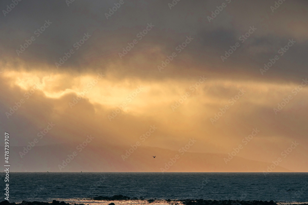Dramatic cloudy sky with sun beam over calm ocean surface. Peaceful and calm atmosphere