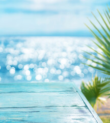 Blue wooden board and blurred sparkling sea at the background. It is possible to place your product. Summer holiday concept.