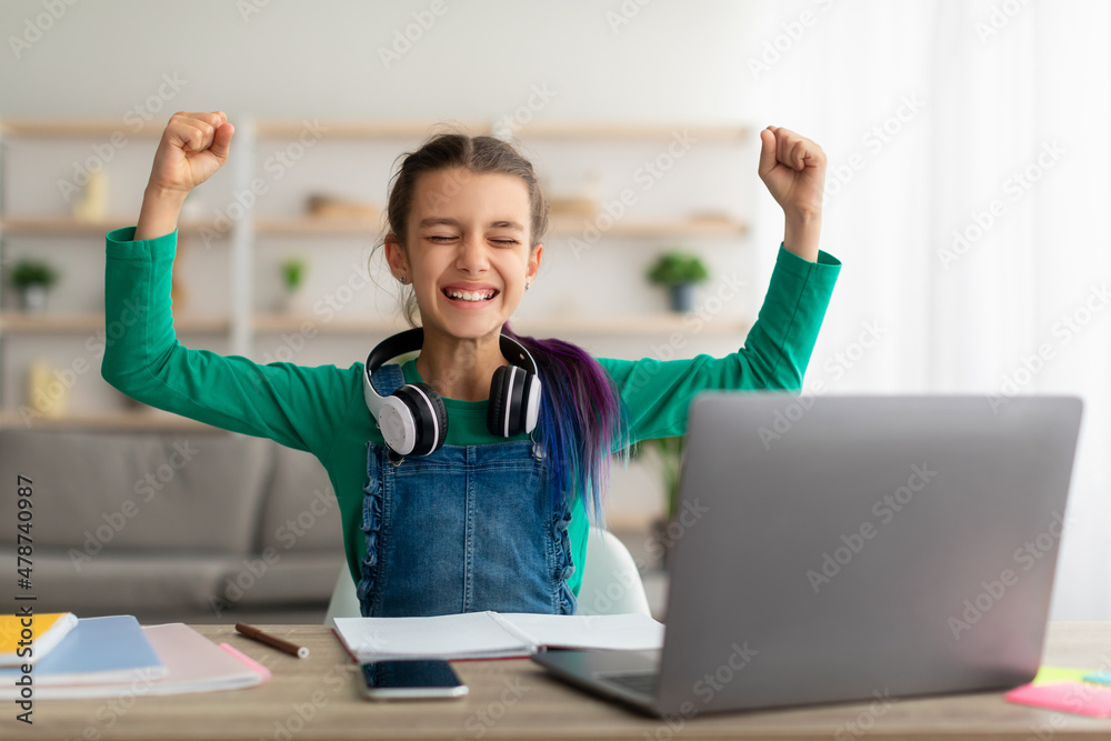 Portrait of emotional girl shaking fists using laptop Portrait of emotional girl shaking fists using laptop