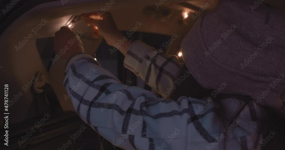Urban style girl decorating inside of her car with lights during road trip life Urban style girl decorating inside of her car with lights during road trip life