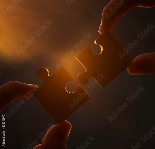 two hands of businessman to connect couple puzzle piece with sky background.Jigsaw alone wooden puzzle against sun rays.one part of whole.symbol of association and connection. business strategy