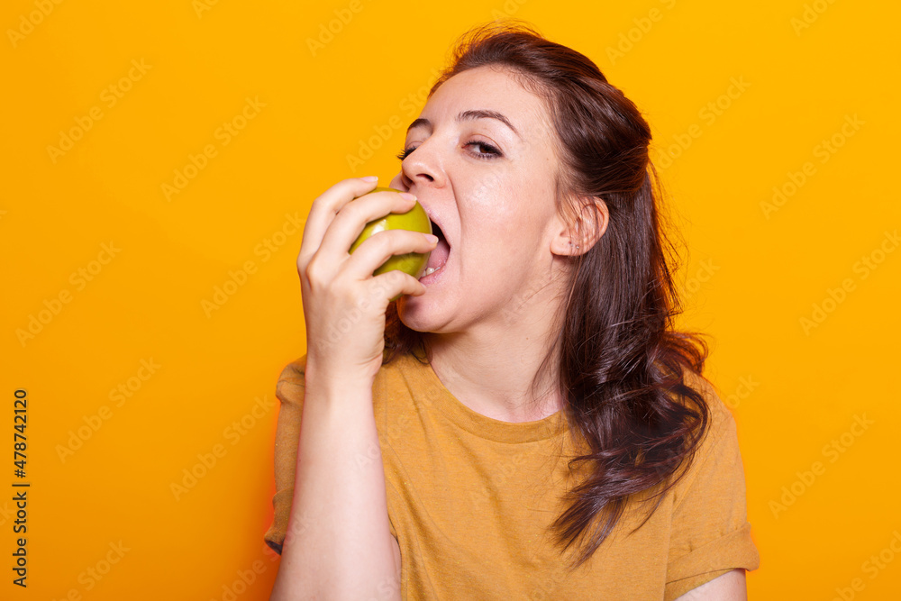 Portrait of healthy woman biting green apple in hand on camera. Caucasian person with vegetarian diet advertising organic sweet snack for natural nutrition and fresh meal. Adult bite fruit Portrait of healthy woman biting green apple in hand on camera. Caucasian person with vegetarian diet advertising organic sweet snack for natural nutrition and fresh meal. Adult bite fruit