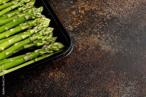Bunch of fresh asparagus, in plastic market  container, on old dark rustic background, with copy space for text