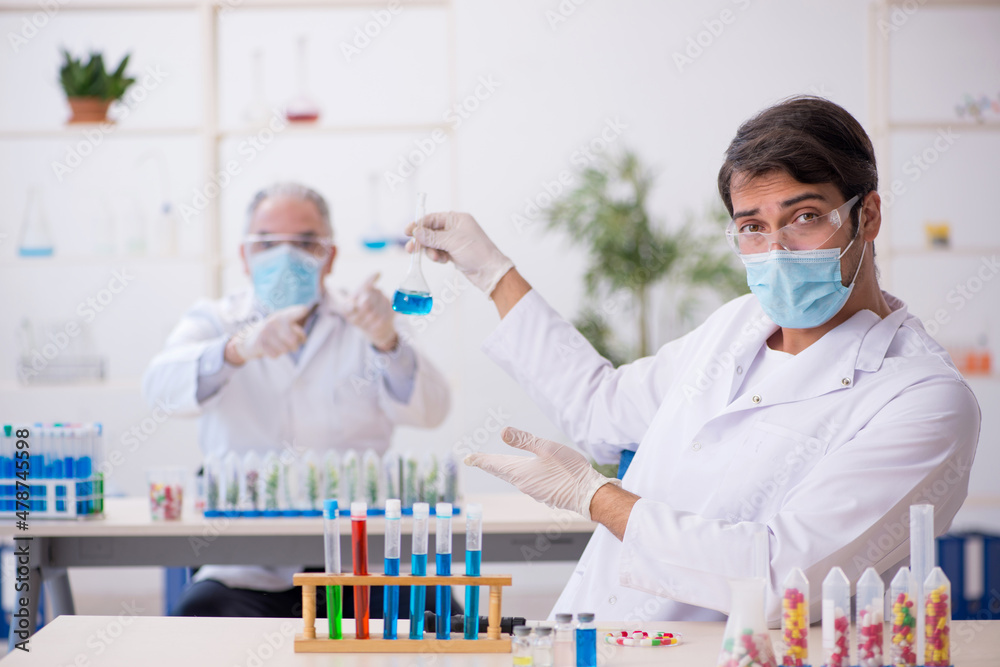 Two male chemists in drugs synthesis concept at the lab Two male chemists in drugs synthesis concept at the lab