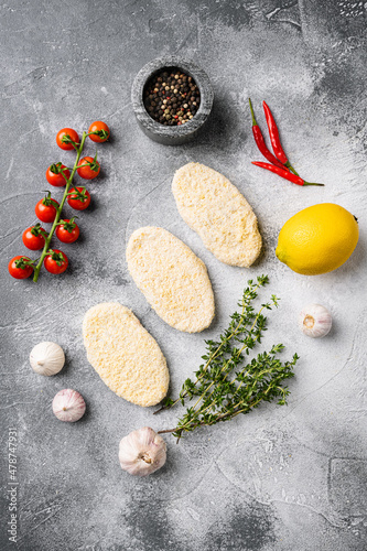 Frozen uncooked fishcake, on gray stone table background, top view flat lay
