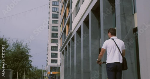 Wallpaper Mural Back view of young businessman riding electric scooter in city. Rear view of handsome young man riding electric scooter on urban city street Torontodigital.ca