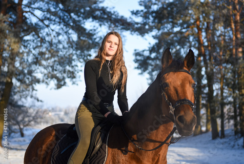 Young girl with horse on winter forest road