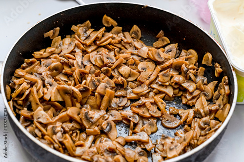 Fried mushrooms, cut into slices, lie in a frying pan on the stove.