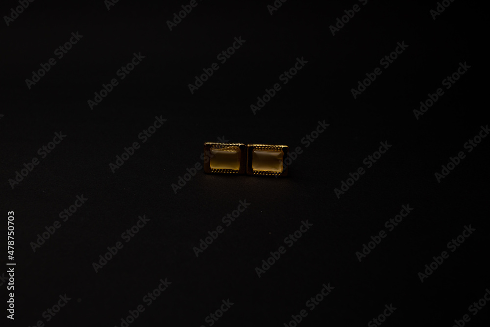 Gold men's cufflinks with stones lie on a black background Gold men's cufflinks with stones lie on a black background