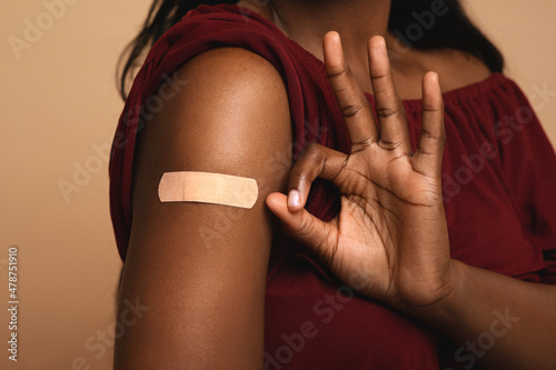Black lady showing shoulder with medical band and okay gesture