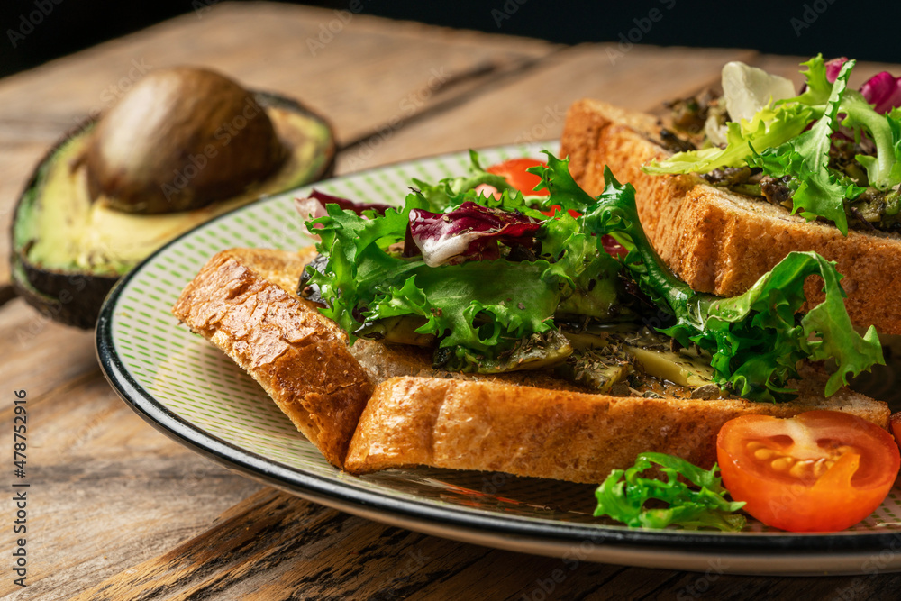 toast with avocado. vegetarian breakfast. Vegan or Vegetarian Toast with mashed avocado, arugula served on wooden board