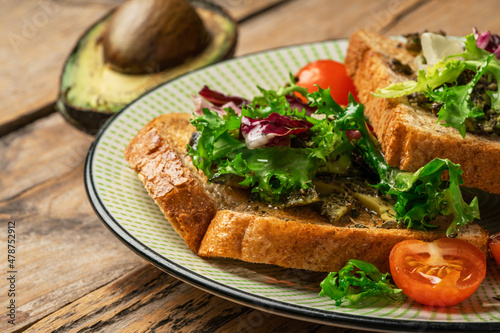 toast with avocado. vegetarian breakfast. Vegan or Vegetarian Toast with mashed avocado, arugula served on wooden board